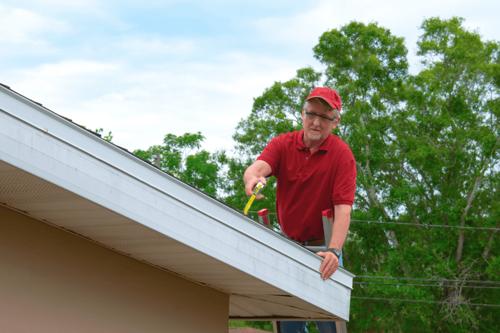 Wind mitigation inspection inspector on a ladder doing inspection on new roof to create a report and risk rating for homeowner to send to their insurance company to receive deductions in policy costs.